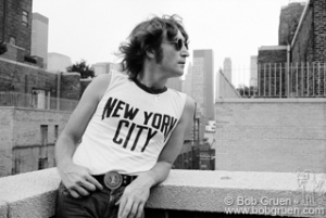 John Lennon wearing NYC t-shirt and leaning on rooftop, NYC. August 29, 1974. © Bob Gruen / www.bobgruen.com Please contact Bob Gruen's studio to purchase a print or license this photo. email: websitemail01@aol.com phone: 212-691-0391
